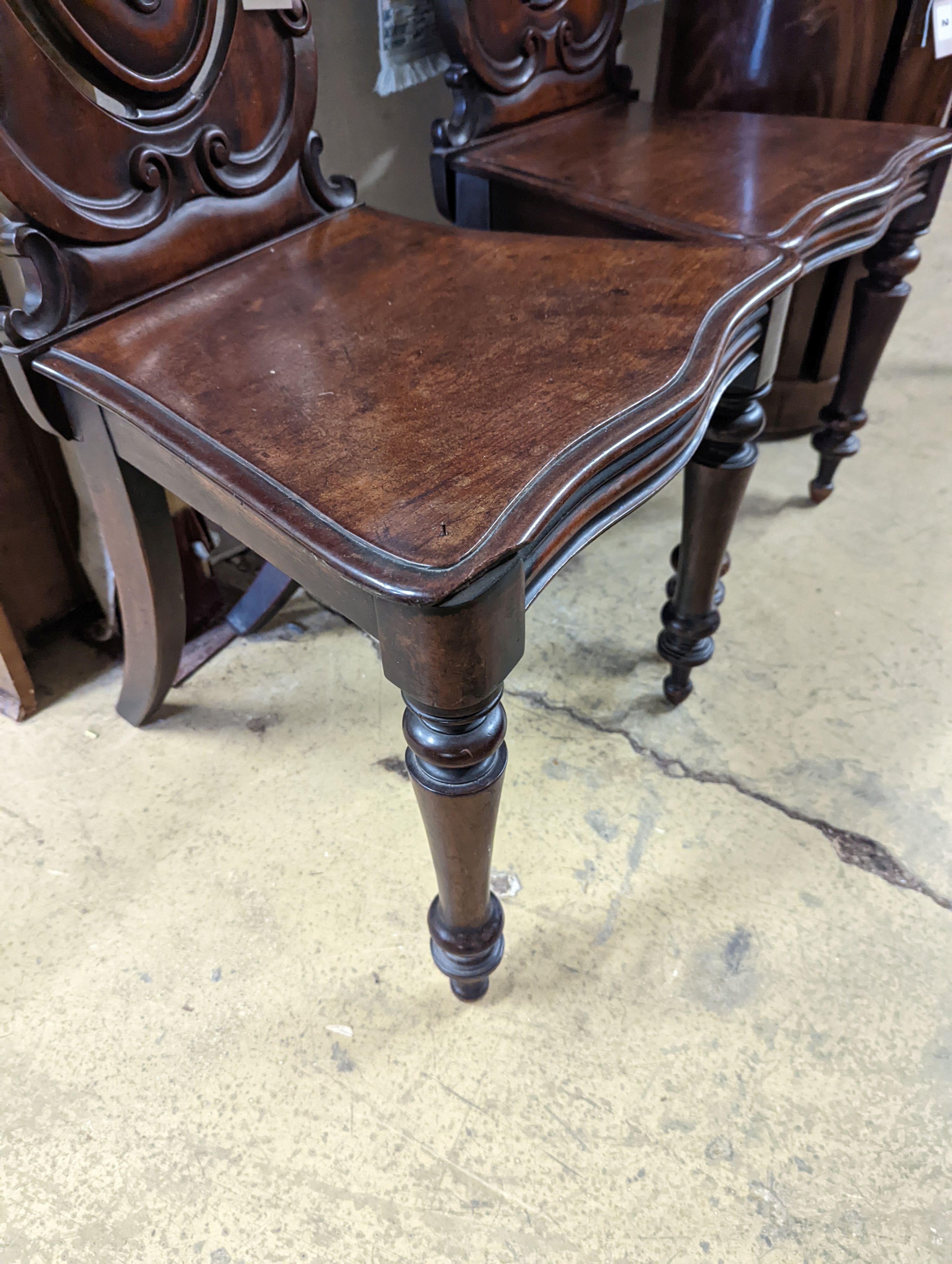 A pair of Victorian carved mahogany hall chairs, a.f.